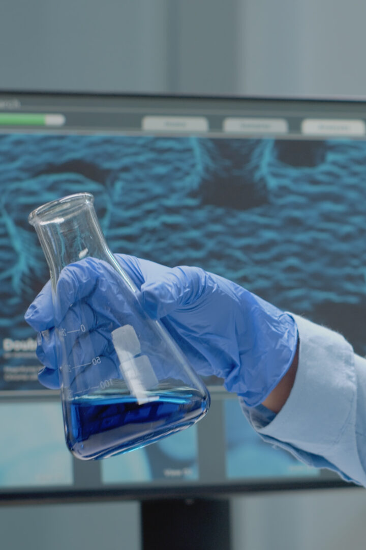 Laboratory scientist analyzing chemical glass beaker with liquid at scientific research clinic. Doctor using biology equipment and glassware studying solution and blood for development